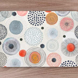 Op de afbeelding: Een laptop skin met een witte achtergrond en een patroon van kleurrijke cirkels. De cirkels zijn in verschillende tinten blauw, rood, oranje en roze. Sommige cirkels hebben een gestippeld patroon, terwijl andere een meer abstract ontwerp hebben.
