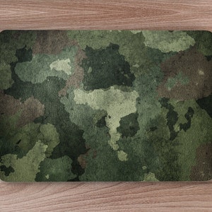 May include: A green and brown camouflage patterned laptop skin. The skin is made of a textured material and has a faded look.