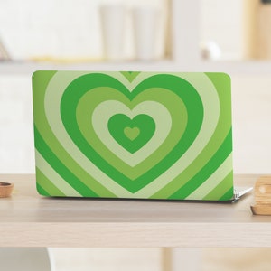 Puede incluir: Una piel para portátil verde con un diseño de corazón concéntrico. El corazón está formado por múltiples tonos de verde, creando un efecto de capas.