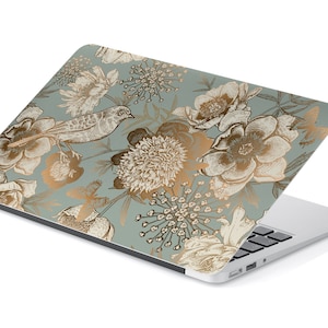 May include: A laptop computer with a floral design on the lid. The design features gold flowers and birds on a light blue background.