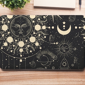 Könnte beinhalten: Eine schwarze Laptop-Haut mit einem goldenen Himmelsdesign mit Sonne, Mond, Sternen und Planeten. Das Design ist filigran und detailliert, mit einer Vintage-Ästhetik.