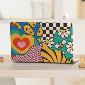 Könnte beinhalten: Ein Laptop mit einem farbenfrohen abstrakten Design mit Herzen, Smiley-Gesichtern, Blumen und Bienen. Das Design ist eine Mischung aus geometrischen Formen und Mustern in Blautönen, Gelb, Rosa, Grün und Rot.