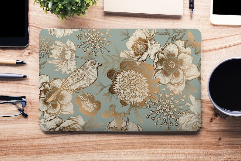 May include: A laptop skin with a floral design featuring a bird, butterflies, and leaves in gold and white on a light blue background.