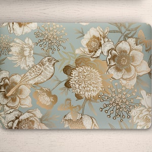 May include: A laptop skin with a floral pattern in gold and white on a light blue background. The design features birds, flowers, and leaves.