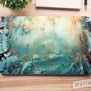 以下が含まれることがあります： ターコイズ、オレンジ、白の筆致が特徴的な抽象的なデザインのラップトップスリーブ。デザインはテクスチャ加工が施されており、筆跡が見えます。スリーブは長方形で、木製の表面にあるようです。