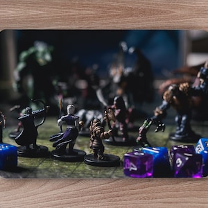 May include: A tabletop game scene with miniature figures of fantasy characters, including a warrior, a mage, and a rogue, battling a large, green monster. The figures are arranged on a game board with dice scattered around them.