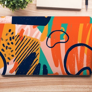 Puede incluir: Un portátil con un diseño abstracto colorido con formas naranjas, amarillas, azules, verdes y rosas. El diseño tiene un aspecto texturizado y pintado a mano.