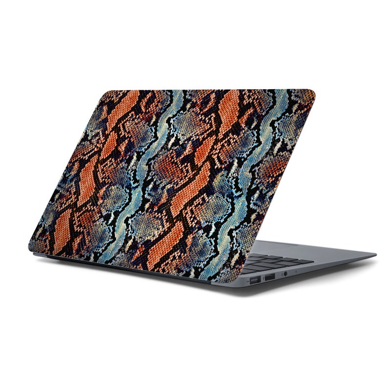 May include: A laptop computer with a snakeskin pattern on the lid. The lid is closed and the laptop is sitting on a white surface.