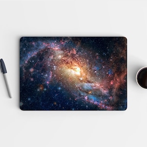 以下が含まれることがあります： 青、ピンク、オレンジの渦巻く色が鮮やかな銀河。銀河は星でいっぱいになっており、明るい黄色の核がある。