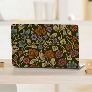 Op de afbeelding: Een laptop met een bloemenpatroon op de deksel. Het ontwerp heeft een donkergroene achtergrond met beige, oranje, roze en blauwe bloemen en bladeren.