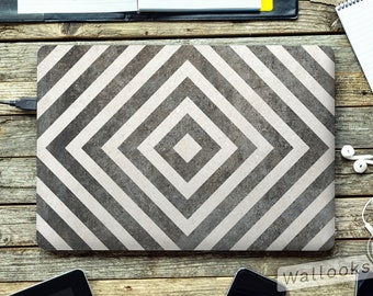 May include: A laptop computer with a grey and white geometric pattern on the lid. The pattern is made up of diagonal stripes that form a diamond shape in the centre. The laptop is on a wooden surface.