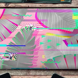 May include: A laptop computer with a pink and gray tropical leaf design. The design features a glitch effect with colorful lines and geometric shapes.