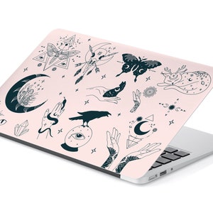 May include: A pink laptop skin with a black and white design featuring various mystical symbols, including moons, stars, hands, eyes, a raven, a butterfly, and a cat.
