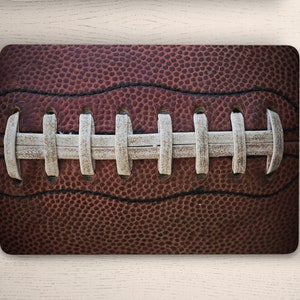 May include: Close-up of a brown leather football with white laces. The laces are stitched in a pattern of parallel lines.