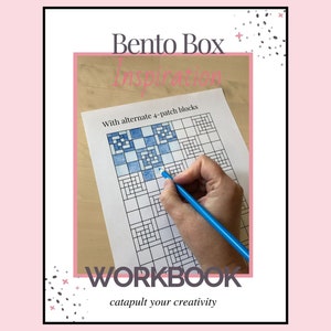 May include: A workbook titled "Bento Box Inspiration" with the text "With alternate 4-patch blocks" and "WORKBOOK catapult your creativity". The workbook has a grid pattern with blue and white squares. A hand is holding a blue pencil and coloring in the grid.