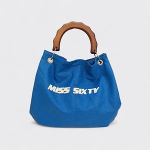 Puede incluir: Bolso azul con asa de madera. El bolso tiene las palabras "MISS SIXTY" en letras plateadas en la parte delantera. El bolso está hecho de un material texturizado y tiene anillos de metal plateado donde se sujeta el asa.