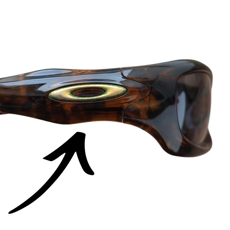 Puede incluir: Gafas de sol marrones y negras con un patr&oacute;n de carey. Las gafas de sol tienen un emblema dorado en el lateral. La montura es curvada y tiene un dise&ntilde;o elegante.