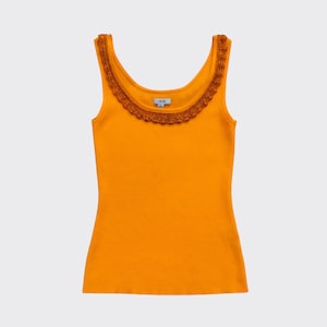 May include: A ribbed, orange tank top with a scoop neckline. The neckline is trimmed with a brown, scalloped lace. The tank top is sleeveless and has a fitted silhouette. The fabric appears to be a soft knit.