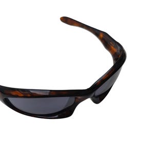 Puede incluir: Gafas de sol deportivas con montura carey marr&oacute;n y lentes gris oscuro. El dise&ntilde;o curvado se adapta a la cara. Un accesorio cl&aacute;sico para actividades al aire libre.