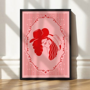 Peut inclure: Une impression encadrée avec un fond rose et une illustration rouge de deux personnes portant des chapeaux et s'embrassant. L'illustration est entourée d'un cadre décoratif.