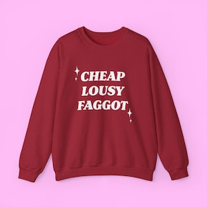 Puede incluir: Sudadera roja con el texto "CHEAP LOUSY FAGGOT" en letras blancas con pequeñas estrellas blancas a cada lado del texto.