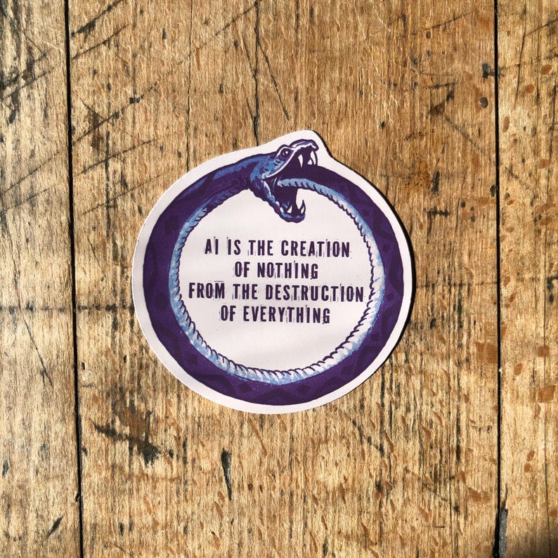 May include: A round sticker with a purple snake eating its tail, with the text "AI IS THE CREATION OF NOTHING FROM THE DESTRUCTION OF EVERYTHING" in white. The sticker is on a wooden surface.