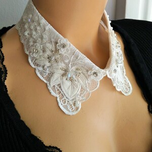 May include: A white lace collar with delicate floral embroidery and sparkling embellishments.