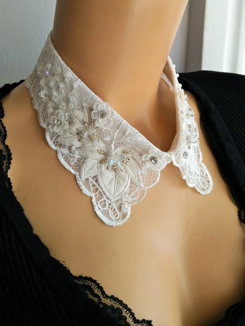 May include: A white lace collar with delicate floral embroidery and sparkling embellishments.