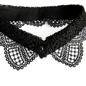 May include: A black lace collar with a scalloped edge. The collar has a simple, elegant design.