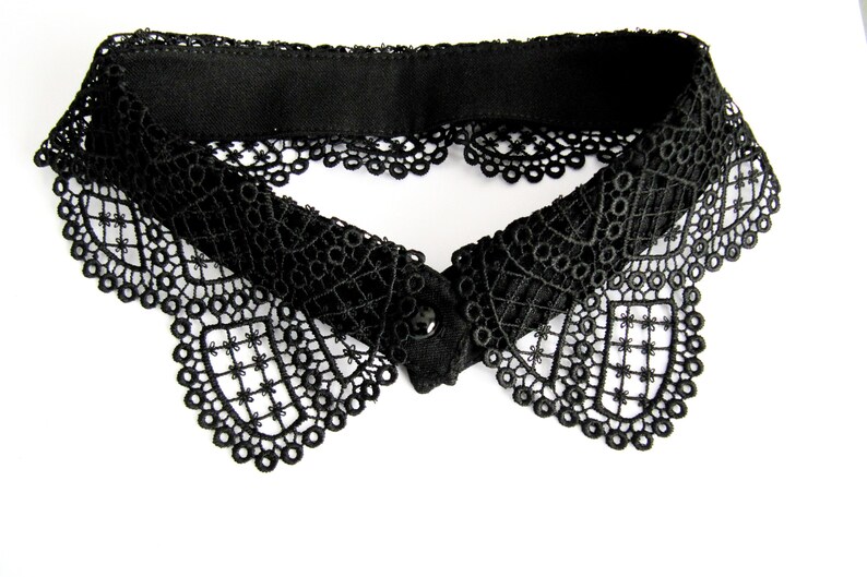 May include: A black lace collar with a scalloped edge. The collar has a simple, elegant design.