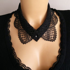 May include: A black lace collar with a button closure. The collar is delicate and intricate, with a scalloped edge.