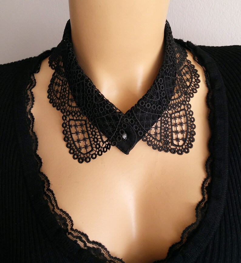 May include: A black lace collar with a button closure. The collar is delicate and intricate, with a scalloped edge.