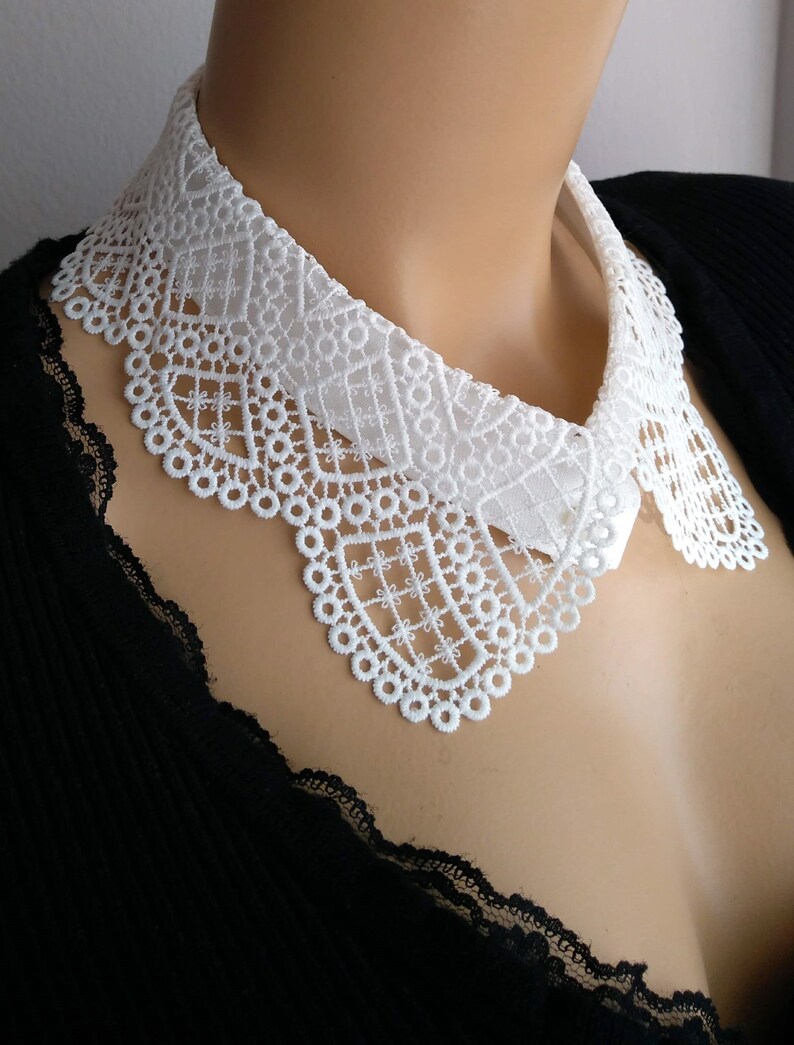 May include: White lace collar with a scalloped edge. The collar is made of delicate lace and is perfect for adding a touch of elegance to any outfit.
