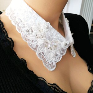 May include: White lace collar with a scalloped edge and beaded embellishments.
