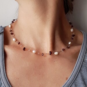 Peut inclure: Un collier délicat avec de petites perles rouge foncé et des perles blanches sur une fine chaîne argentée.
