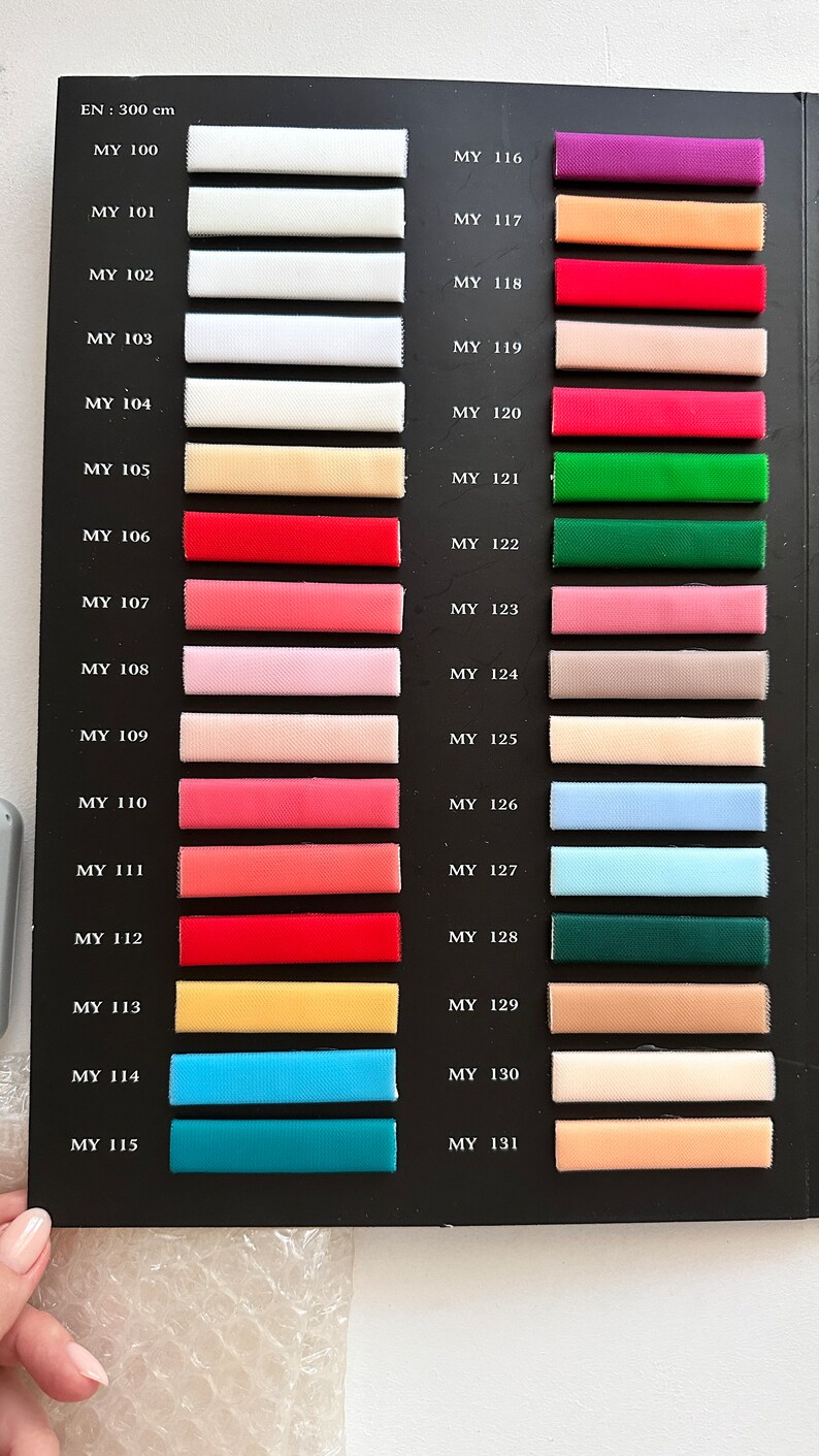 May include: A color chart with 16 fabric swatches, each labeled with a code. The swatches are arranged in two columns, with the codes "MY 100" through "MY 115" on the left and "MY 116" through "MY 131" on the right. The swatches are a variety of colors, including white, red, pink, blue, green, and yellow.