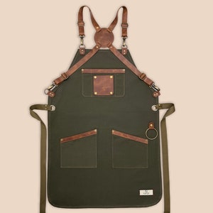 Green cross-back canvas apron with leather straps, utility pockets and metal towel ring