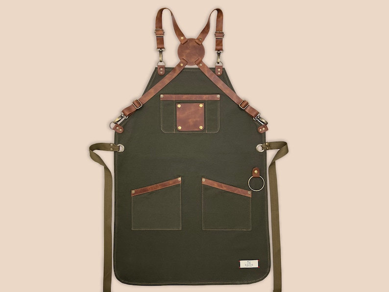Green cross-back canvas apron with leather straps, utility pockets and metal towel ring