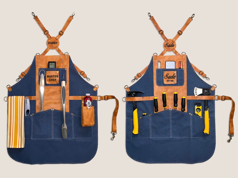 May include: Two blue denim aprons with brown leather accents and straps. One apron has "DADDY" and "MASTER CHEF" labels, the other has "Sade NEW YORK" labels. Each apron has pockets and tool holders.