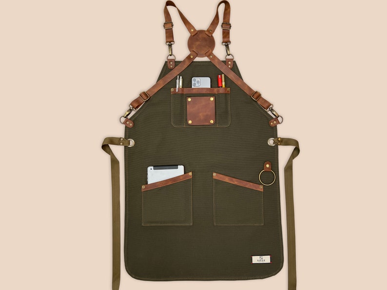 Green personalized canvas apron with brown leather straps, front pockets, towel ring and custom name patch