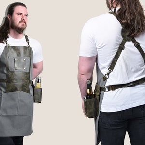 May include: Gray and olive green apron with a leather pocket designed to hold a bottle. The apron has adjustable straps and a pocket on the front. The apron is designed for grilling or bartending.