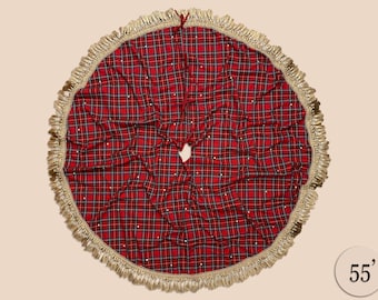 May include: Red and black plaid Christmas tree skirt with a gold fringe trim and white pearl accents. The skirt is 55 inches in diameter.