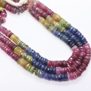 Può includere: Una collana di perline di pietre preziose multicolori. Le perline sono sfaccettate e hanno una forma rotonda. I colori delle perline sono rosa, giallo, verde, blu e viola.