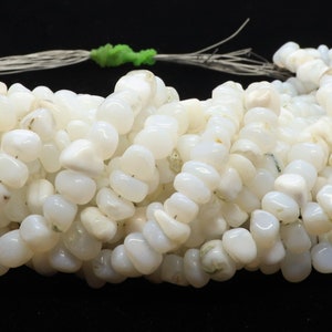 May include: A strand of white opal gemstone beads, each bead is a unique, irregular shape. The beads are strung on a thin cord and are ready to be used for jewelry making.