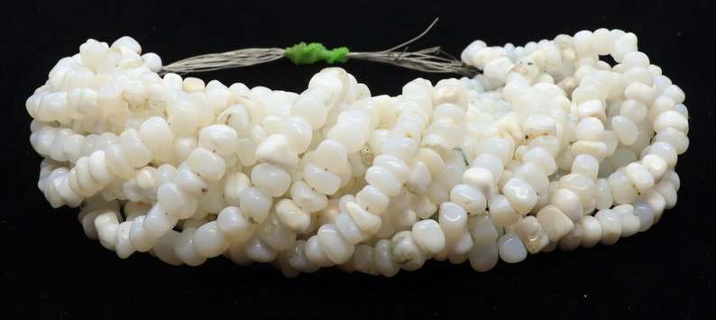 May include: A strand of white opal gemstone beads, each bead is a unique, irregular shape. The beads are strung on a thin cord and are ready to be used for jewelry making.