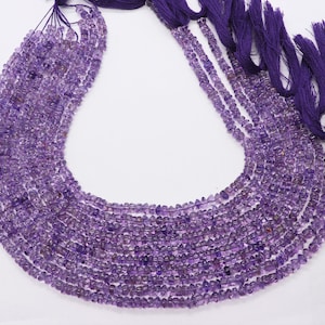 May include: A strand of amethyst gemstone beads, with a purple color, in a faceted shape. The beads are strung on a cord with tassels at the end.