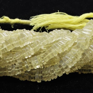 May include: A strand of translucent, light yellow faceted beads. The beads are rectangular in shape and have a slightly iridescent sheen.