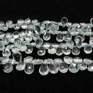 Puede incluir: Una hebra de cuentas de piedra preciosa de aguamarina transparente en forma de lágrima. Las cuentas están enhebradas en un hilo fino y blanco y tienen aproximadamente 10 mm de tamaño.