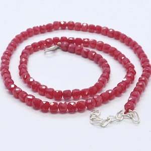 May include: A red gemstone necklace with faceted beads and a silver clasp.