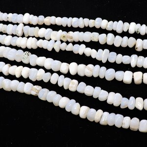 May include: A strand of white gemstone beads, with a smooth, irregular shape. The beads are strung on a clear thread and are arranged in a loose, flowing pattern.